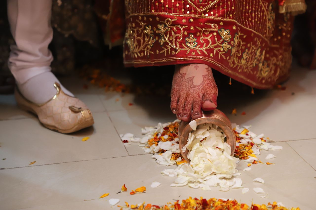 why-choose-us A bride performs a traditional Indian wedding ceremony ritual involving flower petals on the floor.