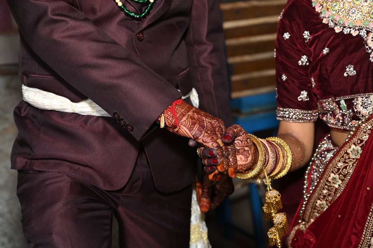 Crafting Captivating Headlines: Your awesome post title goes here Close-up of a couple holding hands, showcasing intricate henna designs and traditional Indian attire during a wedding ceremony.