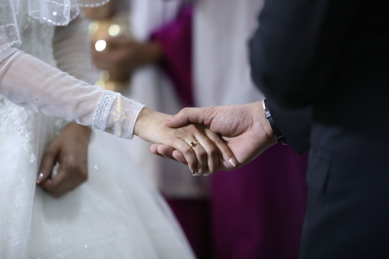 services-img Close-up of a bride and groom holding hands during a wedding ceremony, symbolizing love and unity.