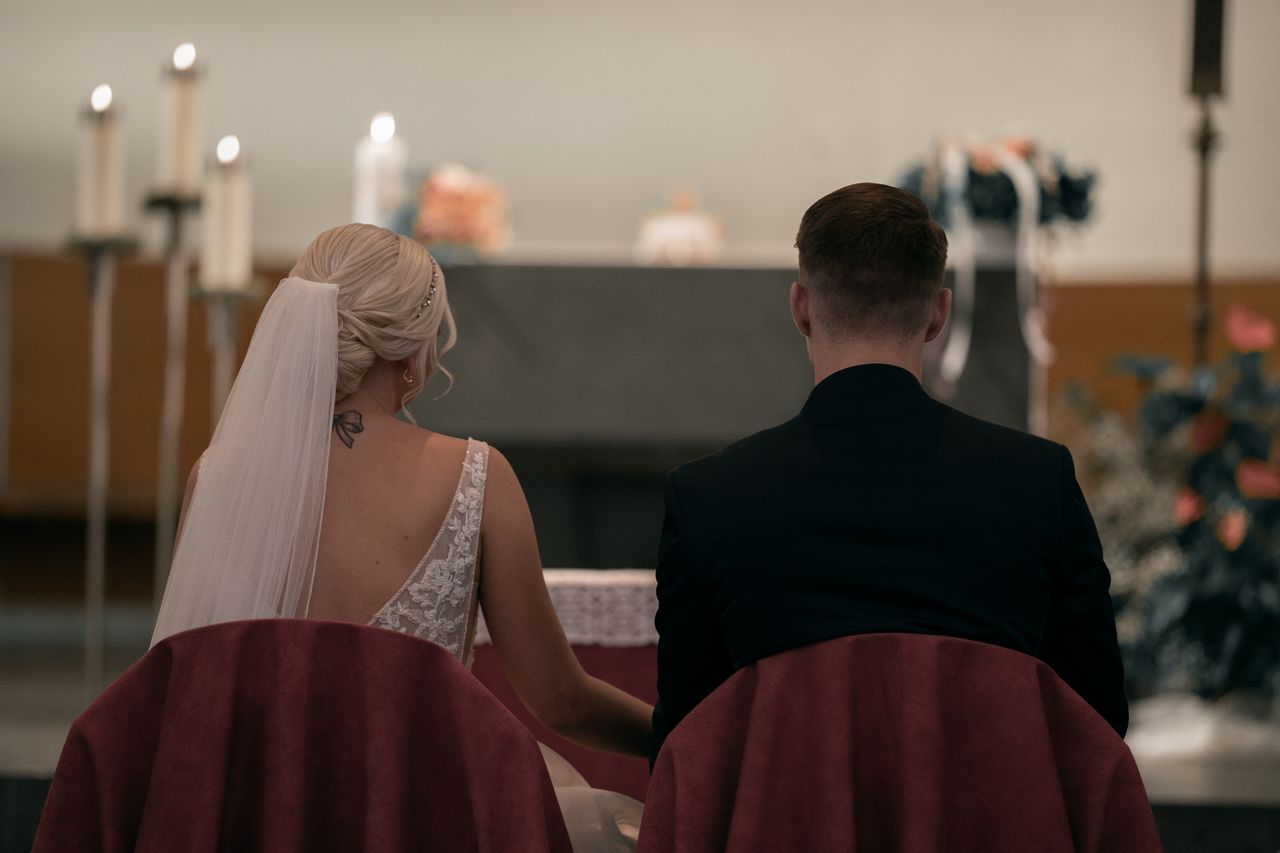 Mastering the First Impression: Your intriguing post title goes here A couple sitting in a church during their wedding ceremony, showcasing love and commitment.